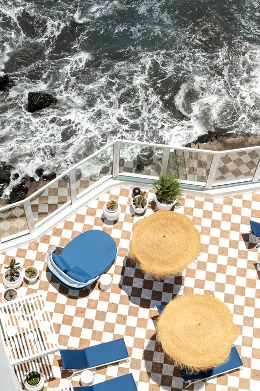 Terrasse carree avec chaises longues et vue sur la mer.