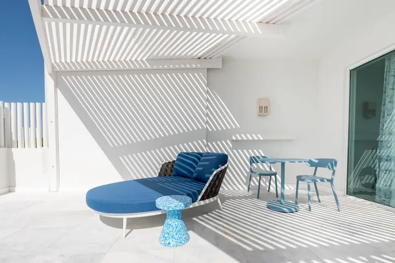 Espace de détente extérieur avec mobilier bleu sous une pergola.