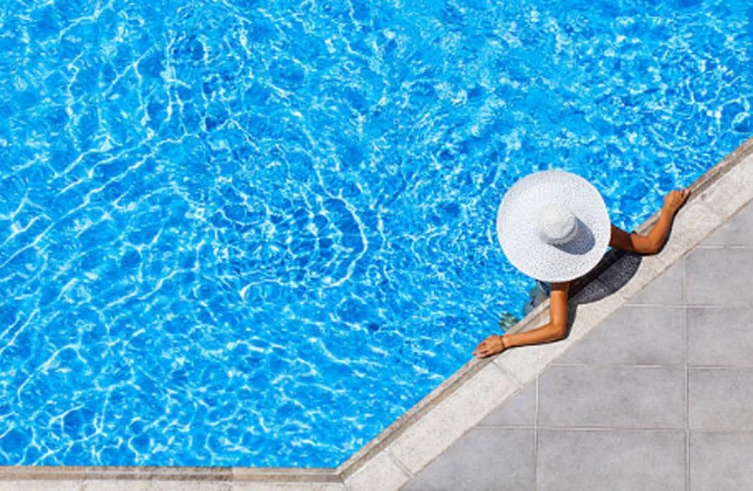 Une personne se détend au bord d'une piscine ensoleillée.