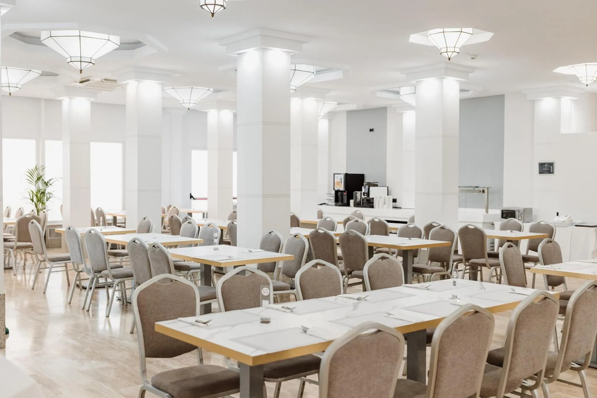Une salle lumineuse est aménagée avec des tables et des chaises pour les repas.