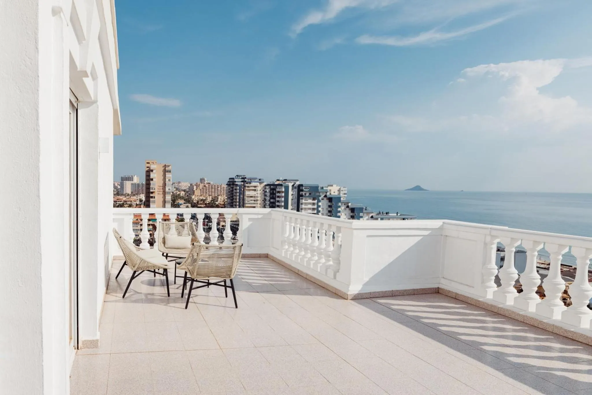Terrasse avec mobilier d'extérieur et vue sur la mer et la ville.