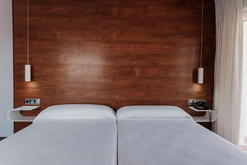 Lit double avec chevet et lampes murales dans une chambre.