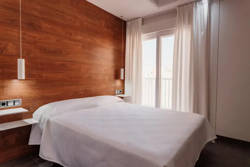 Une chambre lumineuse avec un grand lit recouvert d'une couverture blanche.