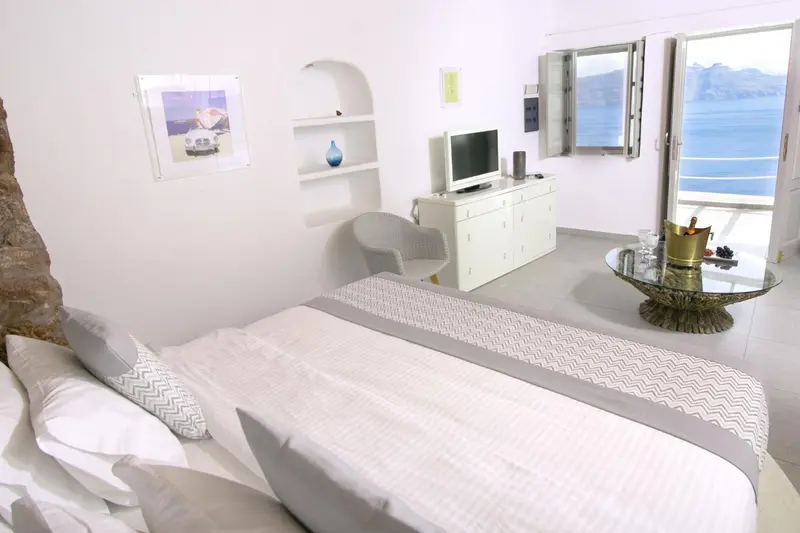 Chambre lumineuse avec un lit fait et une vue sur la mer.