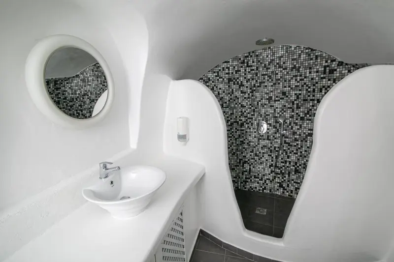 Une salle de bain moderne avec un lavabo blanc et une douche à l'italienne carrelée.