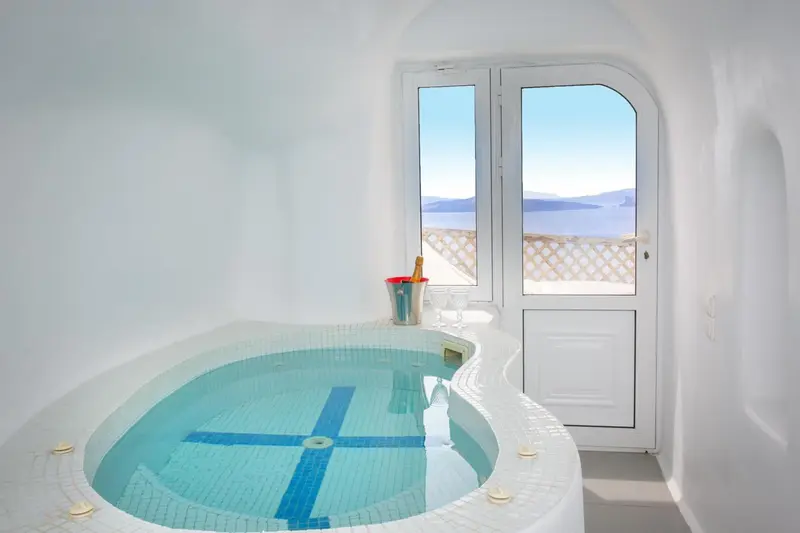 Baignoire d'angle dans une pièce blanche avec vue sur la mer.