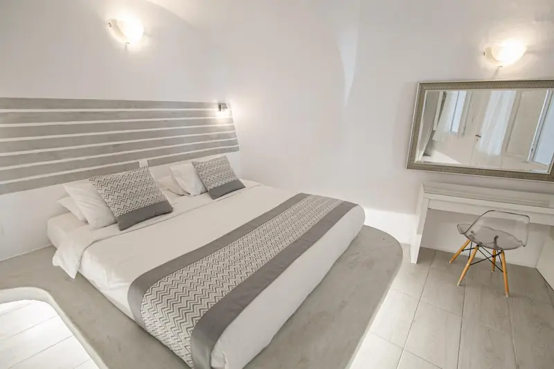 Une chambre lumineuse avec un grand lit et un miroir.
