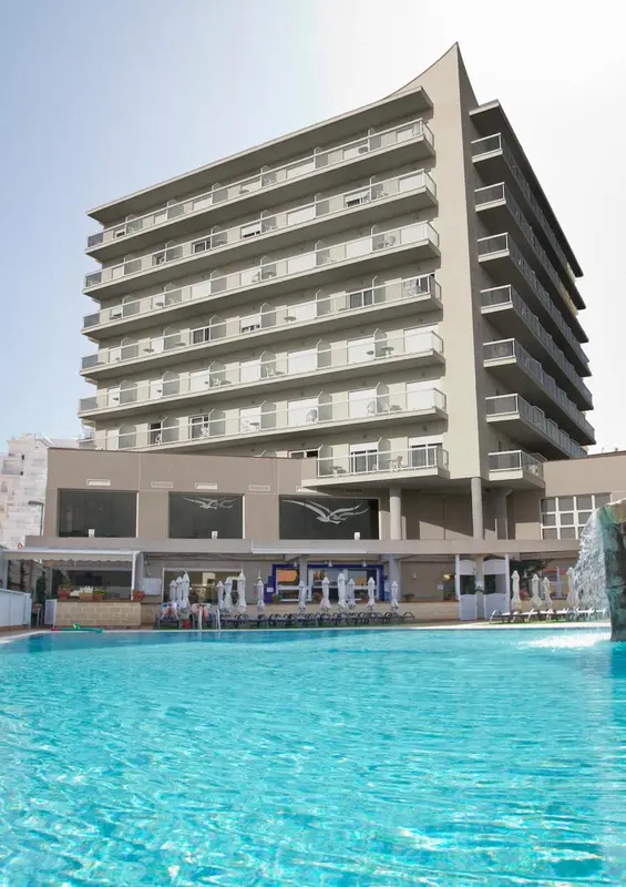 Bâtiment moderne avec des balcons surplombant une piscine turquoise.