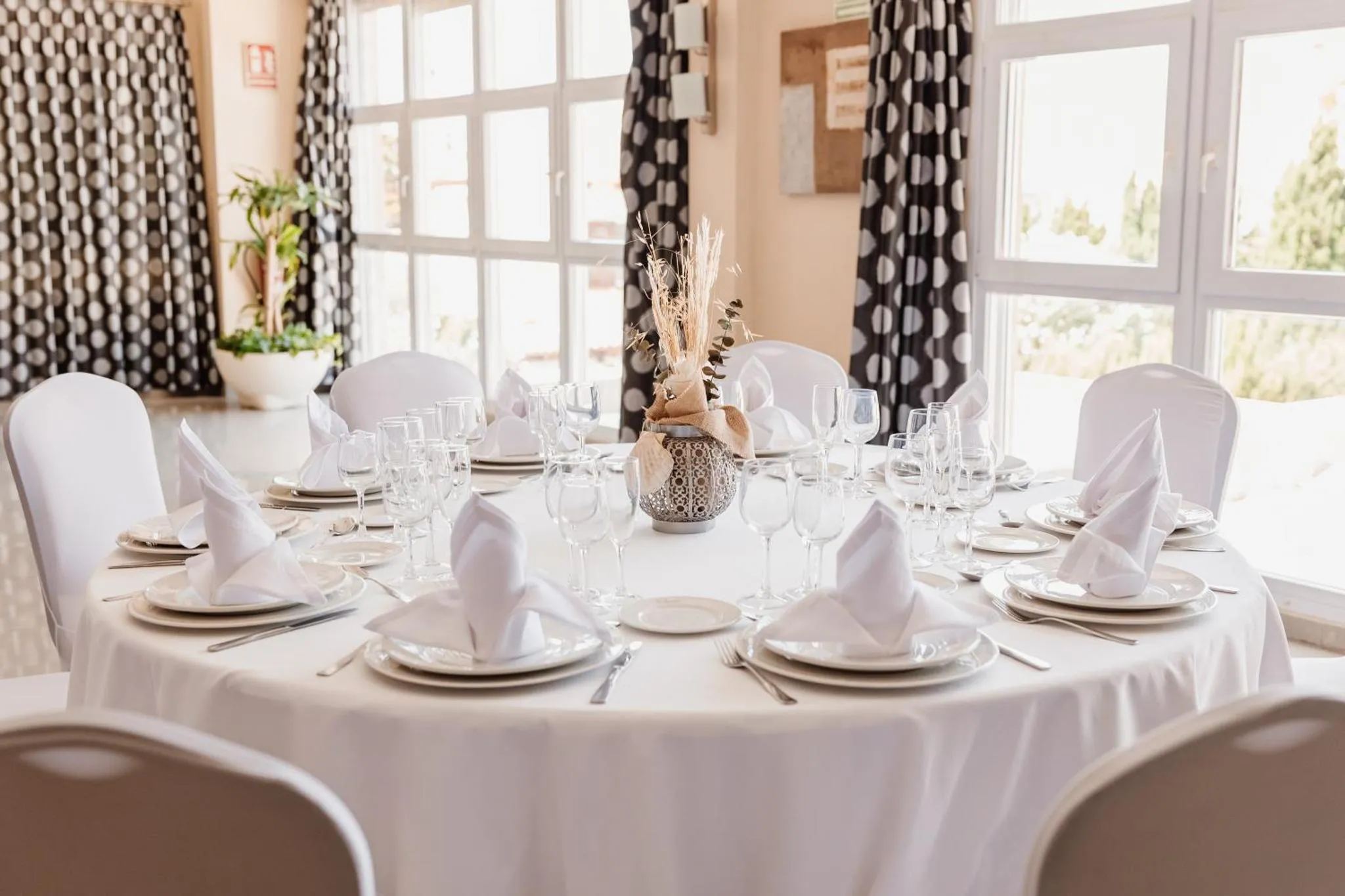 Une table ronde dressée pour un repas avec des couverts et de la vaisselle.