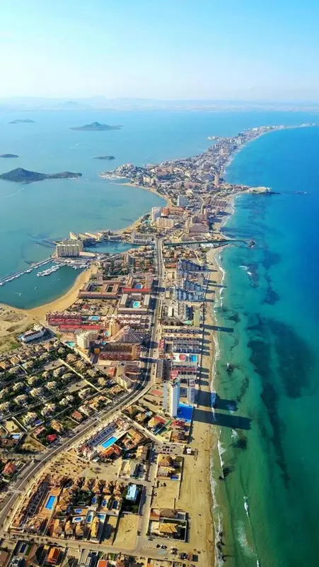 Vue aérienne d'une station balnéaire avec une longue plage et une mer turquoise.