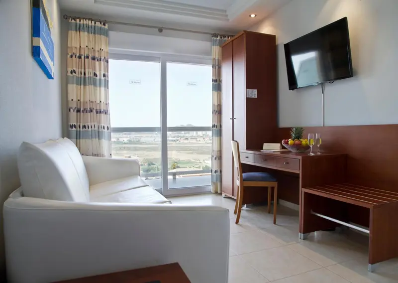 Espace de séjour lumineux avec canapé, bureau et vue sur le paysage.