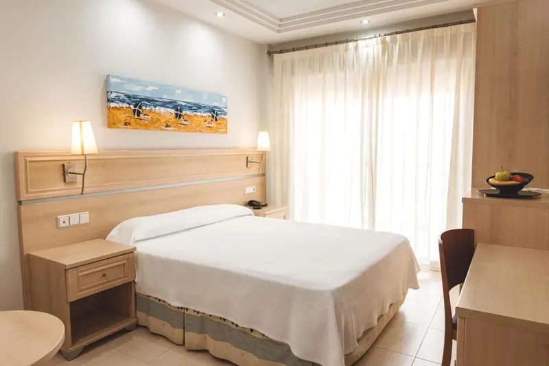 Chambre lumineuse avec un lit double et une décoration murale.