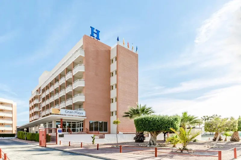 Façade d'un bâtiment de plusieurs étages avec des balcons et une végétation tropicale.
