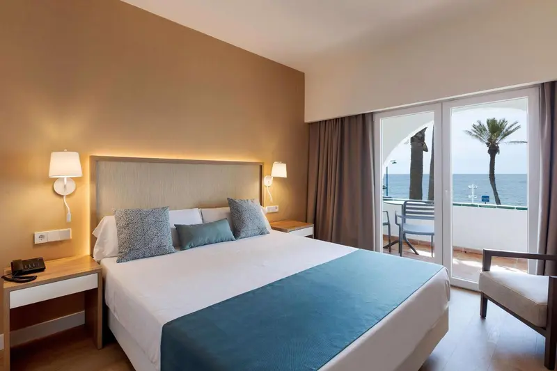 Une chambre lumineuse avec un grand lit et un accès à un balcon.