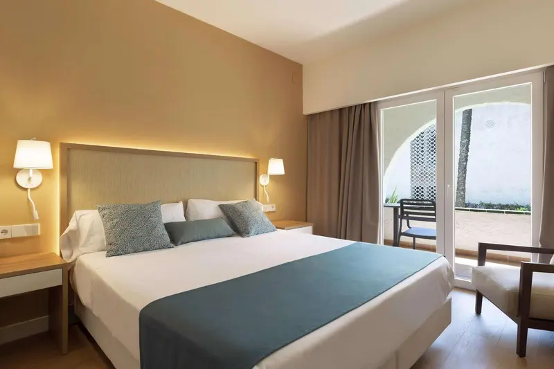 Une chambre lumineuse avec un grand lit et un accès à une terrasse.