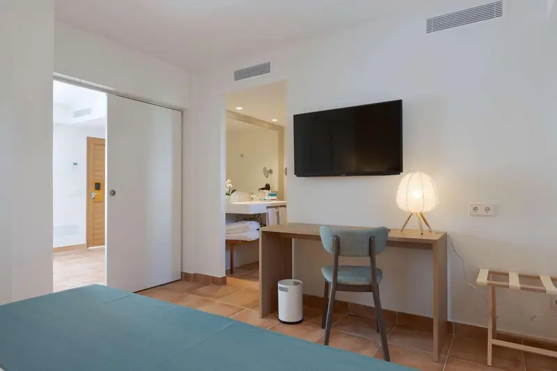 Une chambre lumineuse avec un bureau et un téléviseur mural.