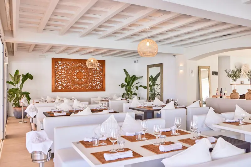 Une salle de restaurant lumineuse avec des tables nappées et une décoration murale en bois.