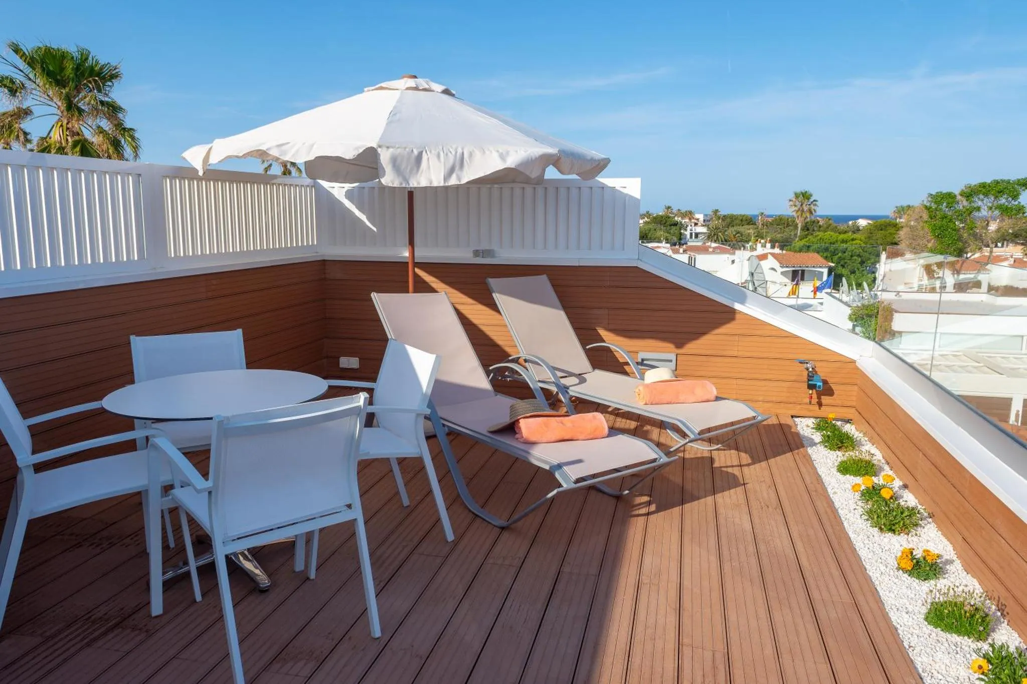Terrasse aménagée avec transats et table basse, vue sur la mer.