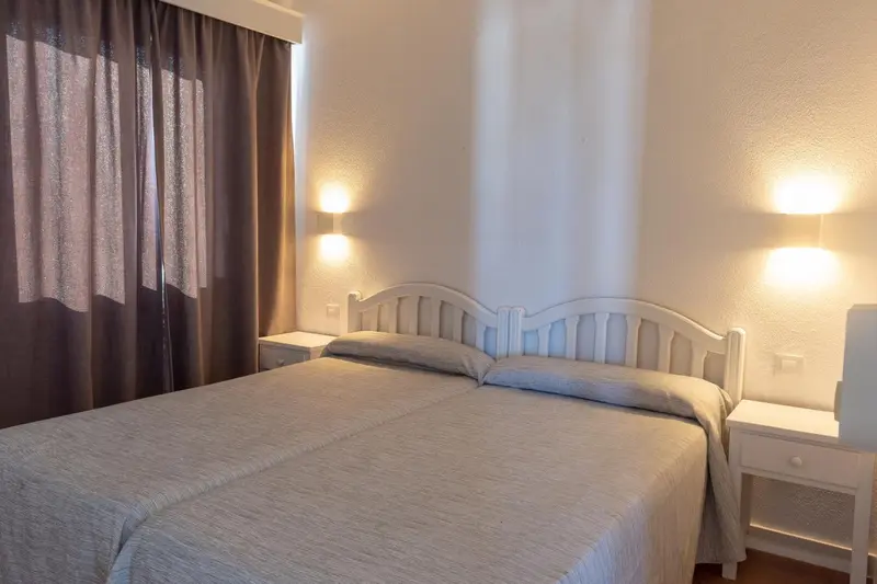 Une chambre lumineuse avec un lit double et des tables de chevet.