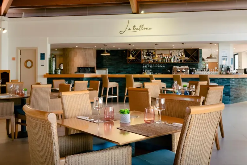 Une salle de restaurant lumineuse avec des tables et un comptoir de bar.