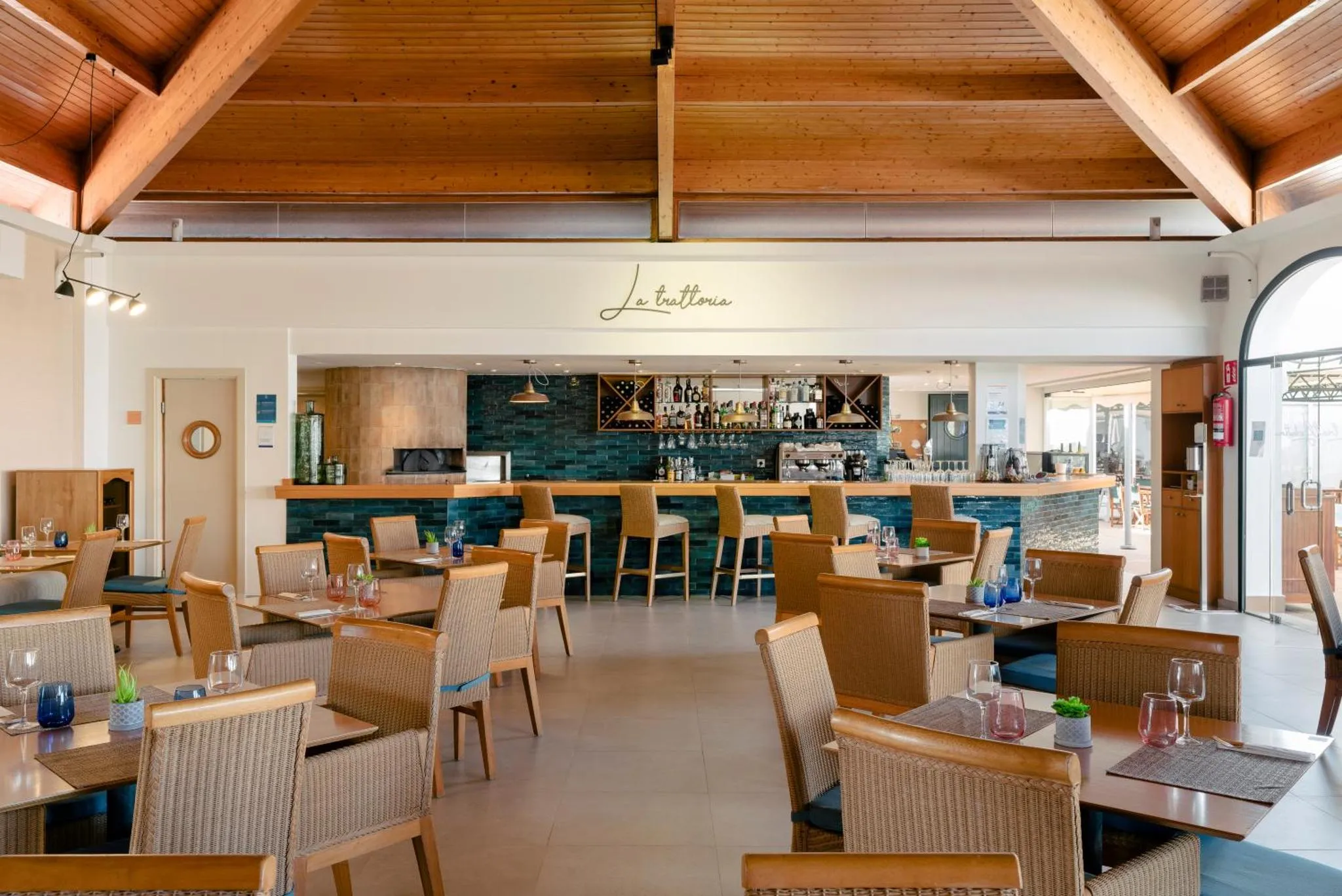 Une salle de restaurant lumineuse avec un bar et des tables disposées sur un sol carrelé.