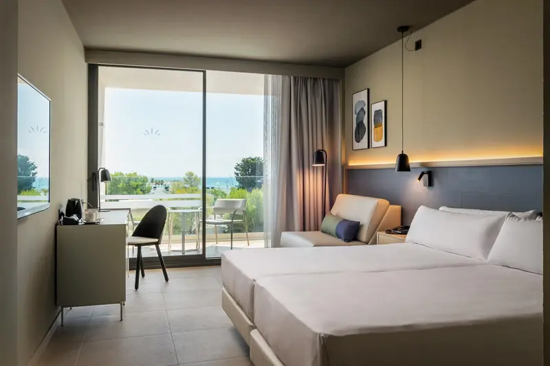 Une chambre lumineuse avec un grand lit et un accès à un balcon.