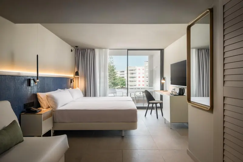 Chambre lumineuse avec un grand lit et une vue sur la ville.