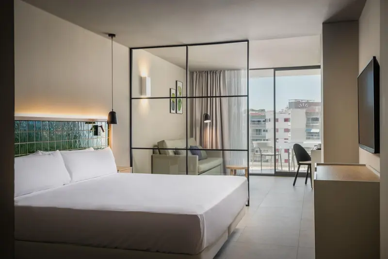 Une chambre lumineuse avec un grand lit et un coin salon.