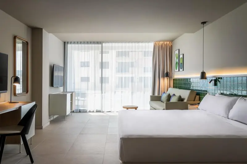 Une chambre lumineuse avec un grand lit et un accès à une terrasse.