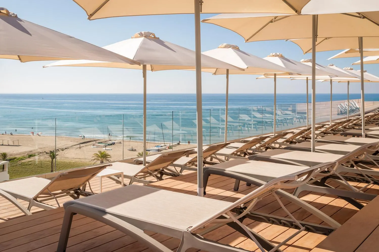 Terrasse ensoleillée avec transats et vue sur la mer.