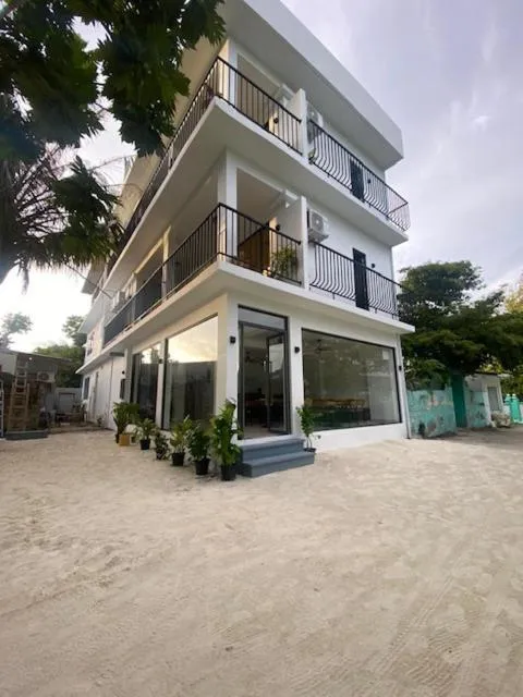 Bâtiment blanc à deux étages avec des balcons et de grandes baies vitrées.