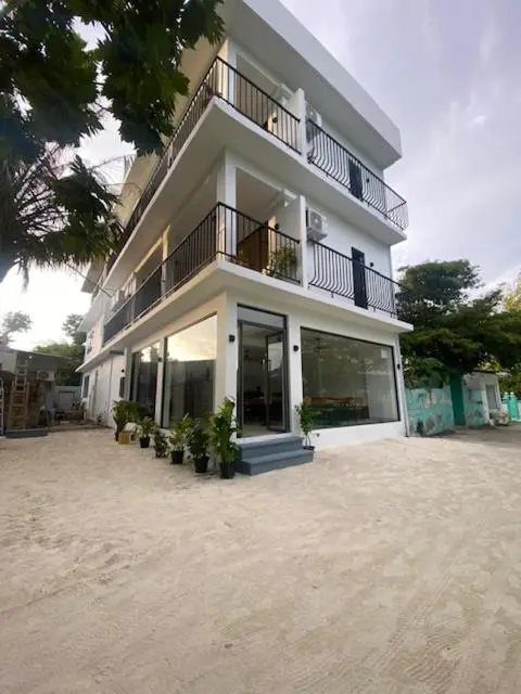 Bâtiment blanc à deux étages avec des balcons et de grandes baies vitrées.