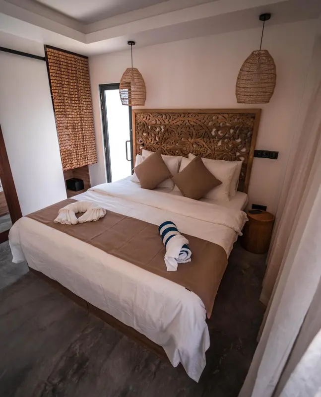 Une chambre avec un grand lit décoré d'une tête de lit sculptée et de coussins.