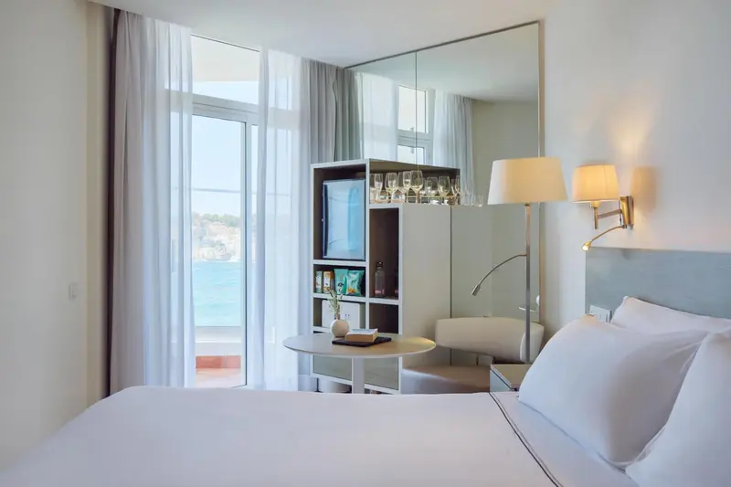 Chambre lumineuse avec un grand lit et vue sur la mer.