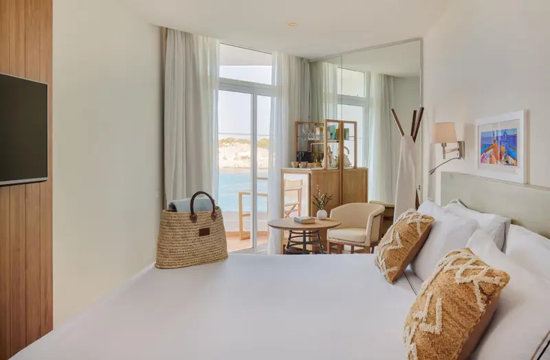 Une chambre lumineuse avec un lit fait et une vue sur la mer.