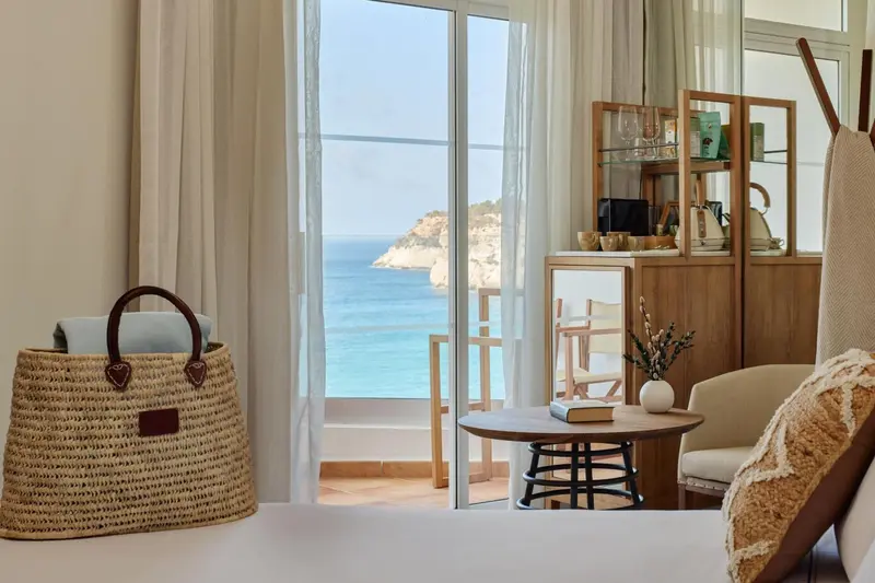 Une chambre lumineuse avec vue sur la mer depuis un balcon.