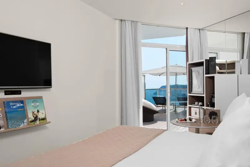 Une chambre lumineuse s'ouvre sur une terrasse avec vue sur la mer.