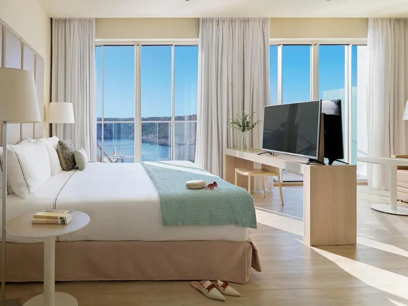 Une chambre lumineuse avec un grand lit et une vue sur la mer.