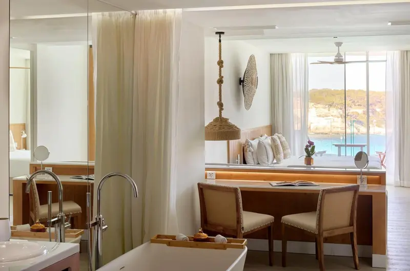 Une chambre lumineuse avec un coin salon et une vue sur la mer.