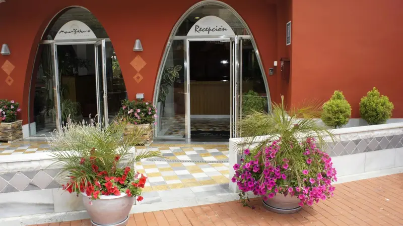 Entrée d'un bâtiment avec des pots de fleurs et un comptoir d'accueil.