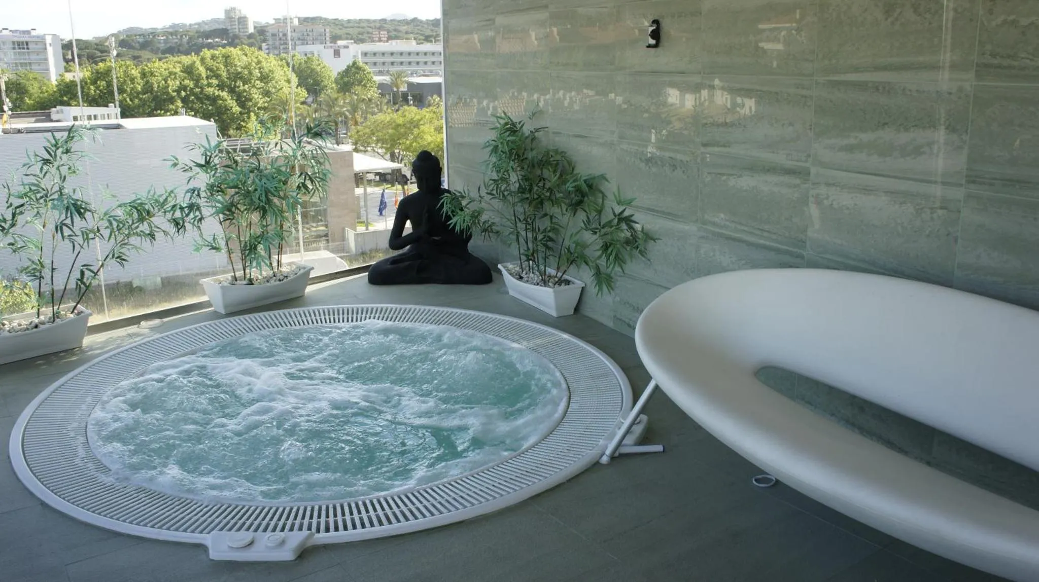Une personne est assise en tailleur près d'un jacuzzi sur une terrasse.