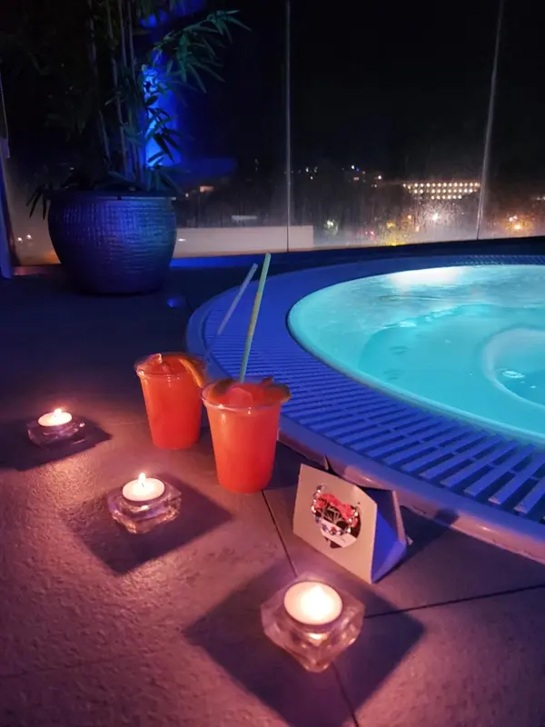 Un jacuzzi extérieur illuminé avec des boissons et des bougies.