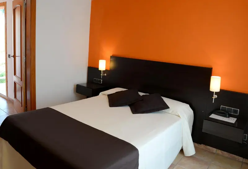 Une chambre avec un grand lit recouvert d'une courtepointe blanche et de coussins noirs.