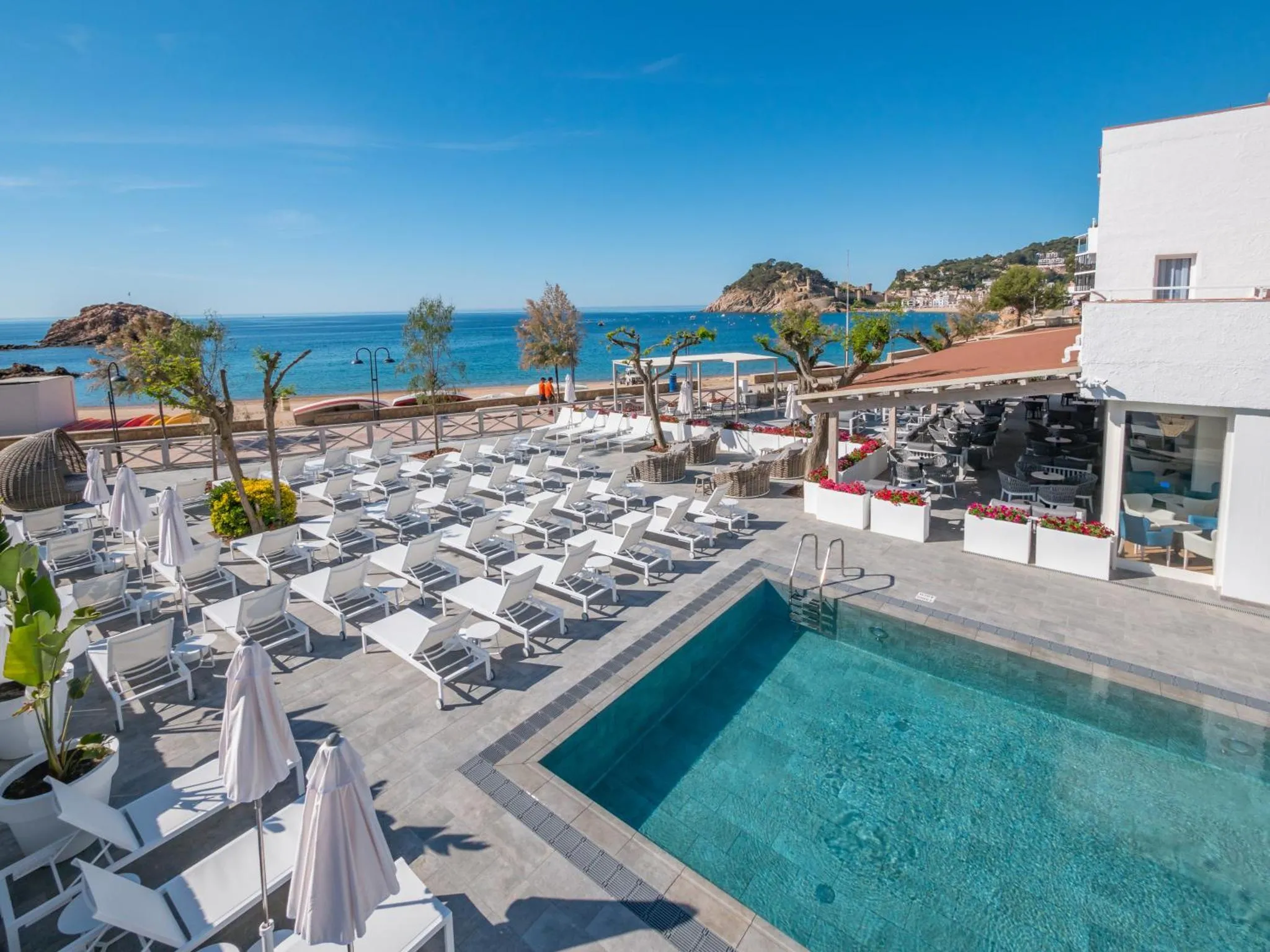 Terrasse avec transats et piscine face à la mer.