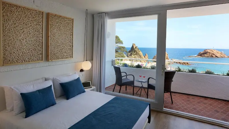 Une chambre lumineuse s'ouvre sur une terrasse avec vue sur la mer.