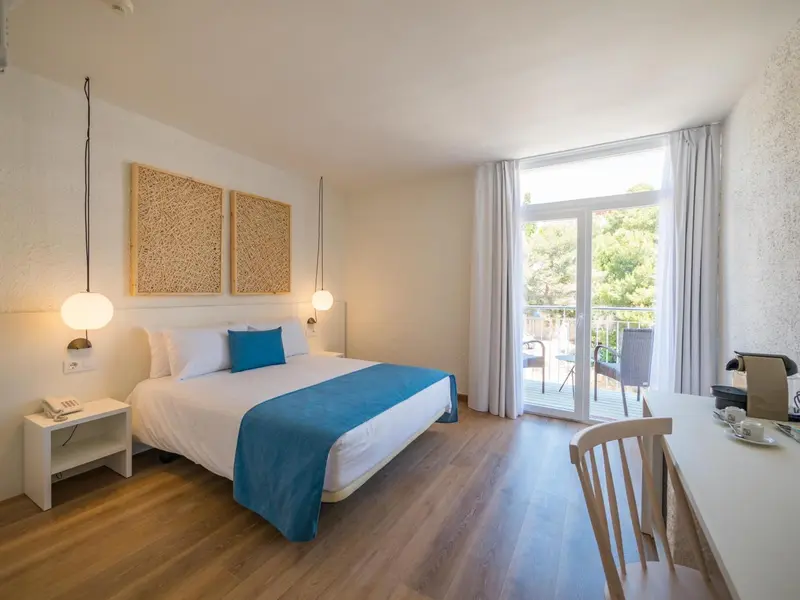 Une chambre lumineuse avec un grand lit et un accès à un balcon.
