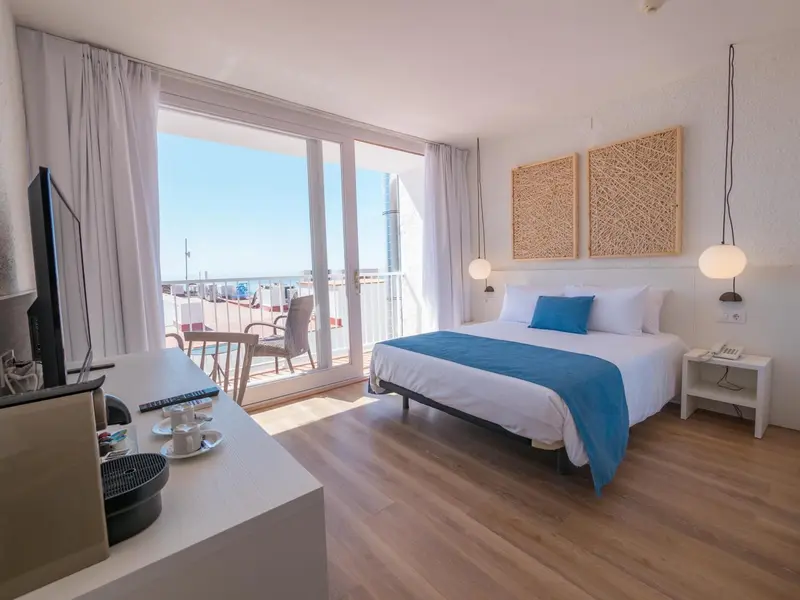 Chambre lumineuse avec un grand lit et vue sur la mer.