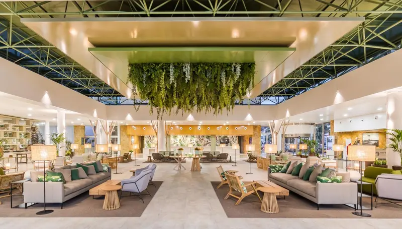 Vaste espace de détente intérieur avec canapés, fauteuils et végétation suspendue.