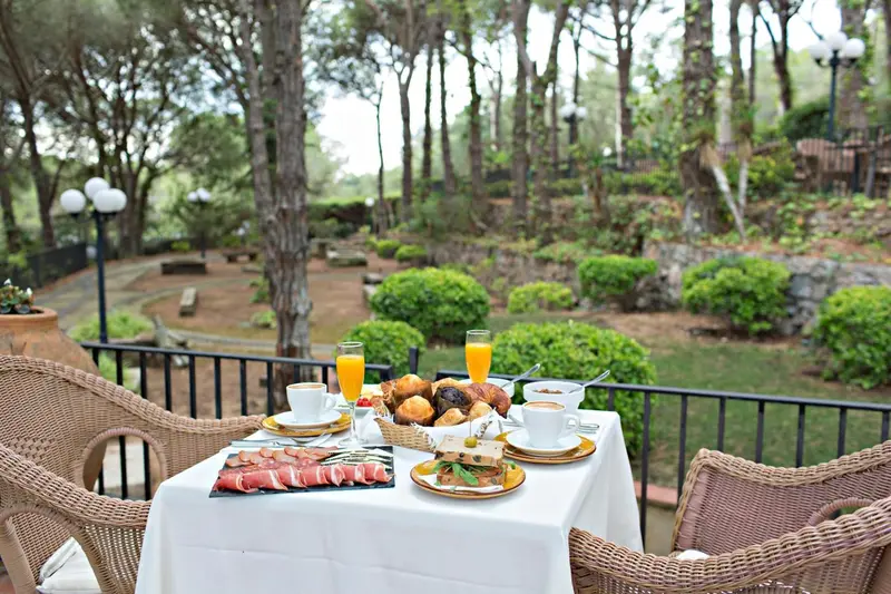 Une table est dressée avec un petit-déjeuner sur une terrasse ensoleillée.