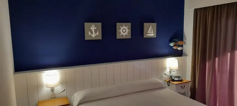 Une chambre avec un lit simple et des décorations murales sur le thème de la mer.